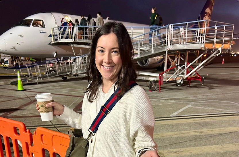Mom with travel essentials and coffee in hand at airport with family