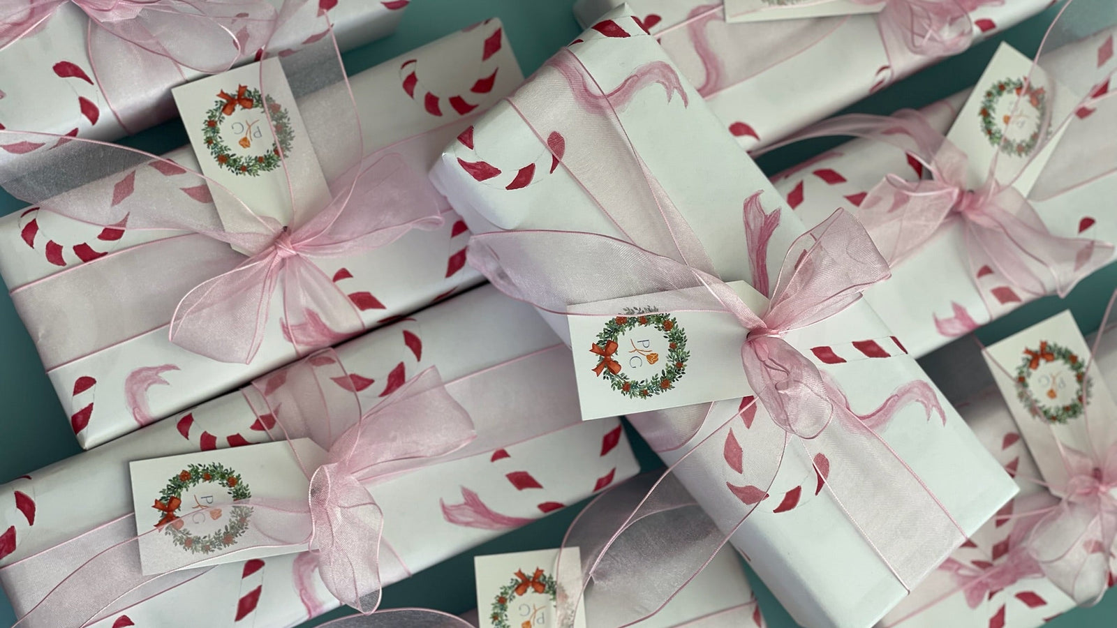 Gift boxes with pink ribbons and decorative labels on a teal background