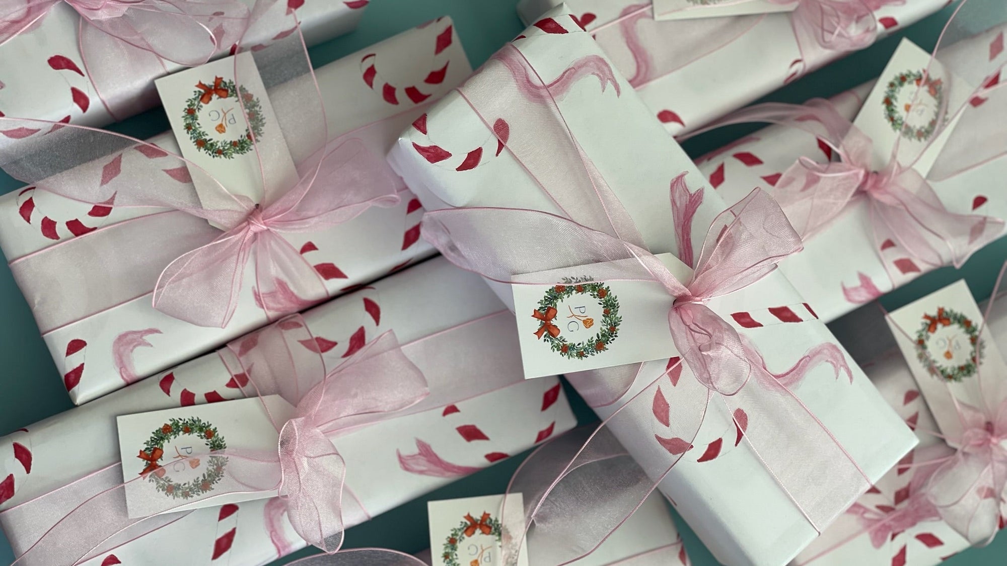 Gift boxes with pink ribbons and decorative labels on a teal background